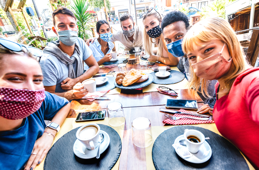 friends taking a mask-on selfie while eating outside