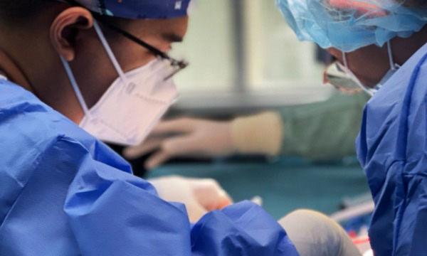 professionals in surgical attire performing a procedure