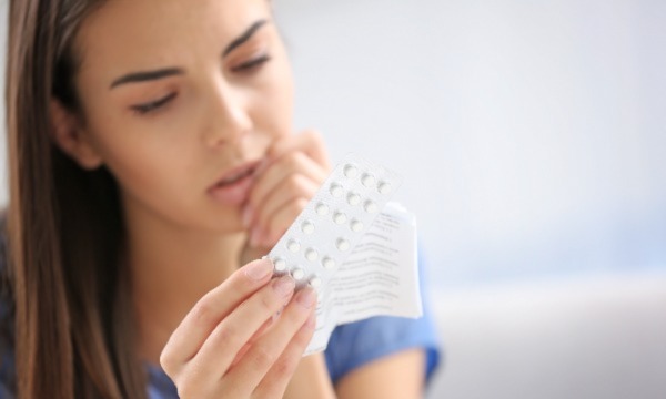 woman examining pills with concern