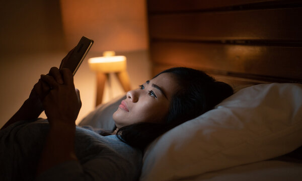 woman using her phone in bed