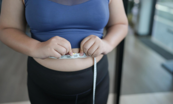 person measuring their waist with a tape measure